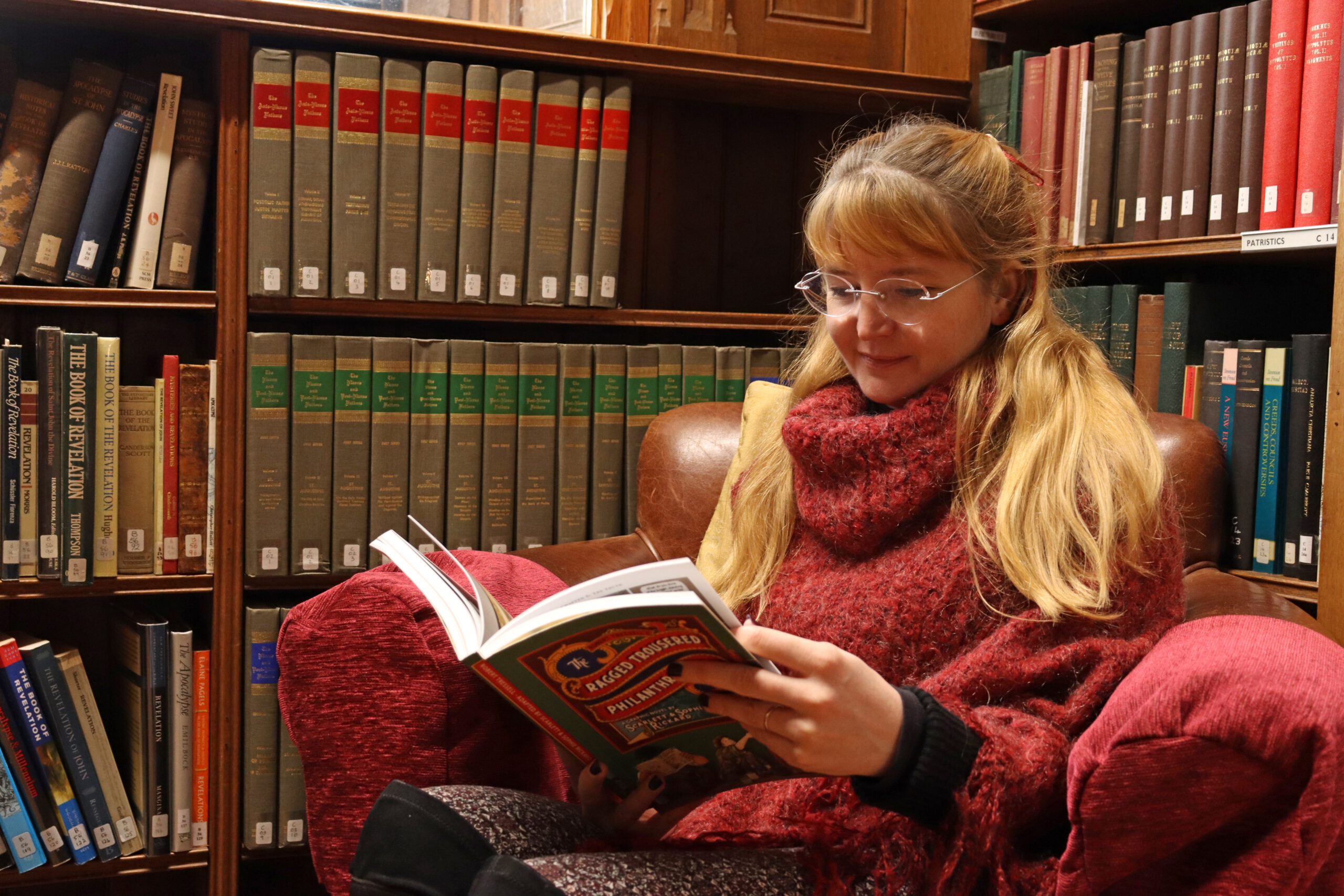 Sophie Rickard reading a book while sitting on a Reading rooms chair