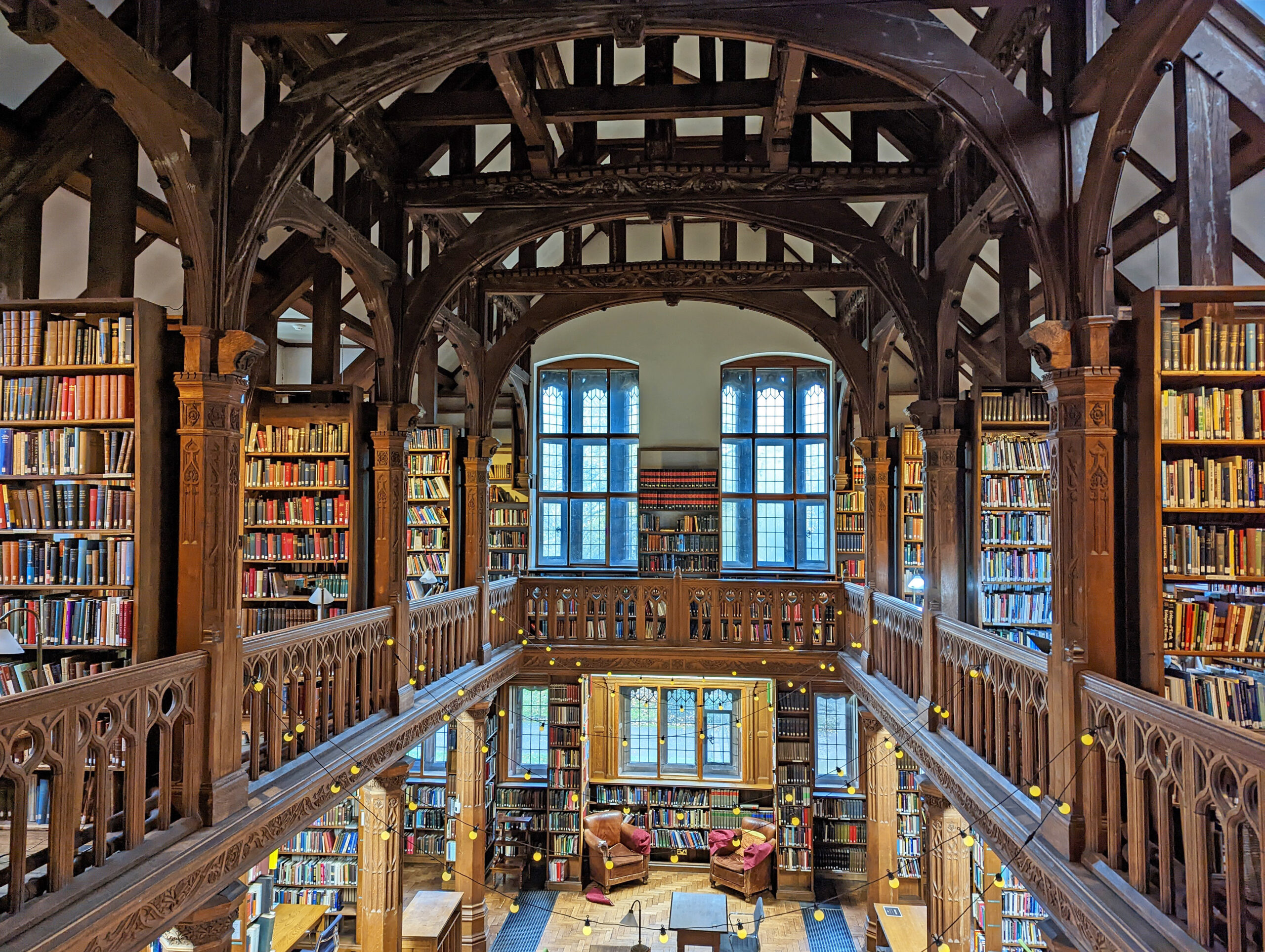 A shot from the top gallery of the Theology Room. It shows pillars, baulstrades, bookshelves and windows at the far end